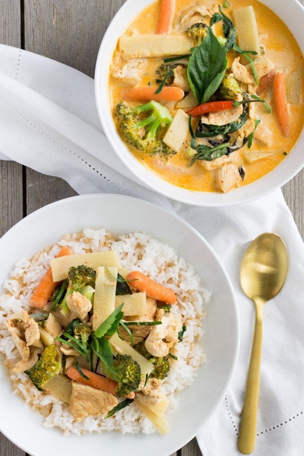 Overhead view of red curry chicken in a large bowl with veggies and another smaller bowl with rice and the curry on top.