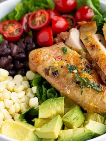 Grilled chicken, avocado, corn, black beans, and tomatoes in a bowl.