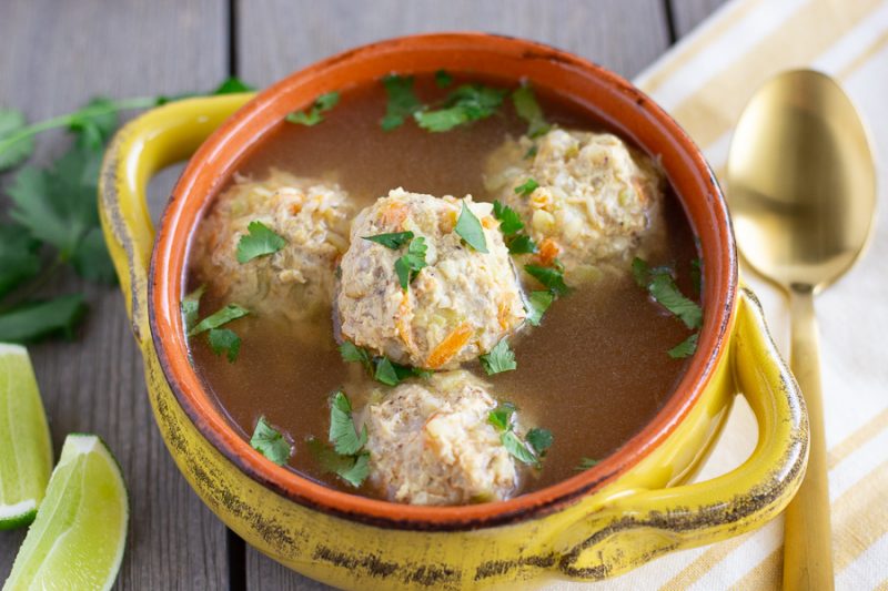 Up close view of albondigas in a yellow bowl. 