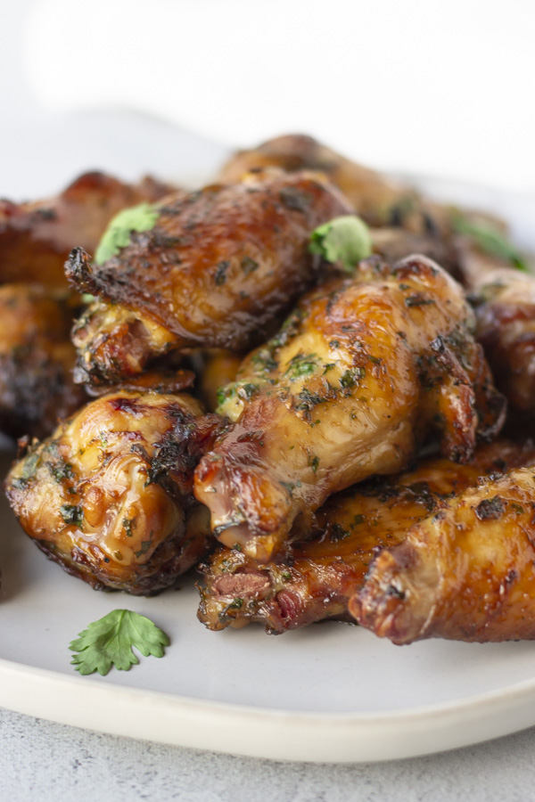 Finished wings piled on a plate topped with cilantro.