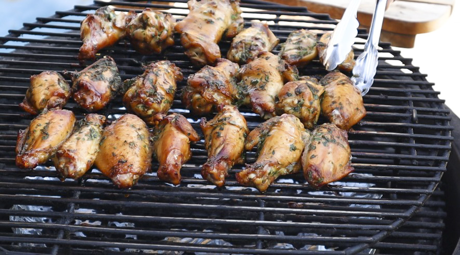 Chicken on the Grill being flipped over with metal tongs.