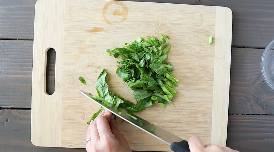 Chinese broccoli on a cutting board being sliced.
