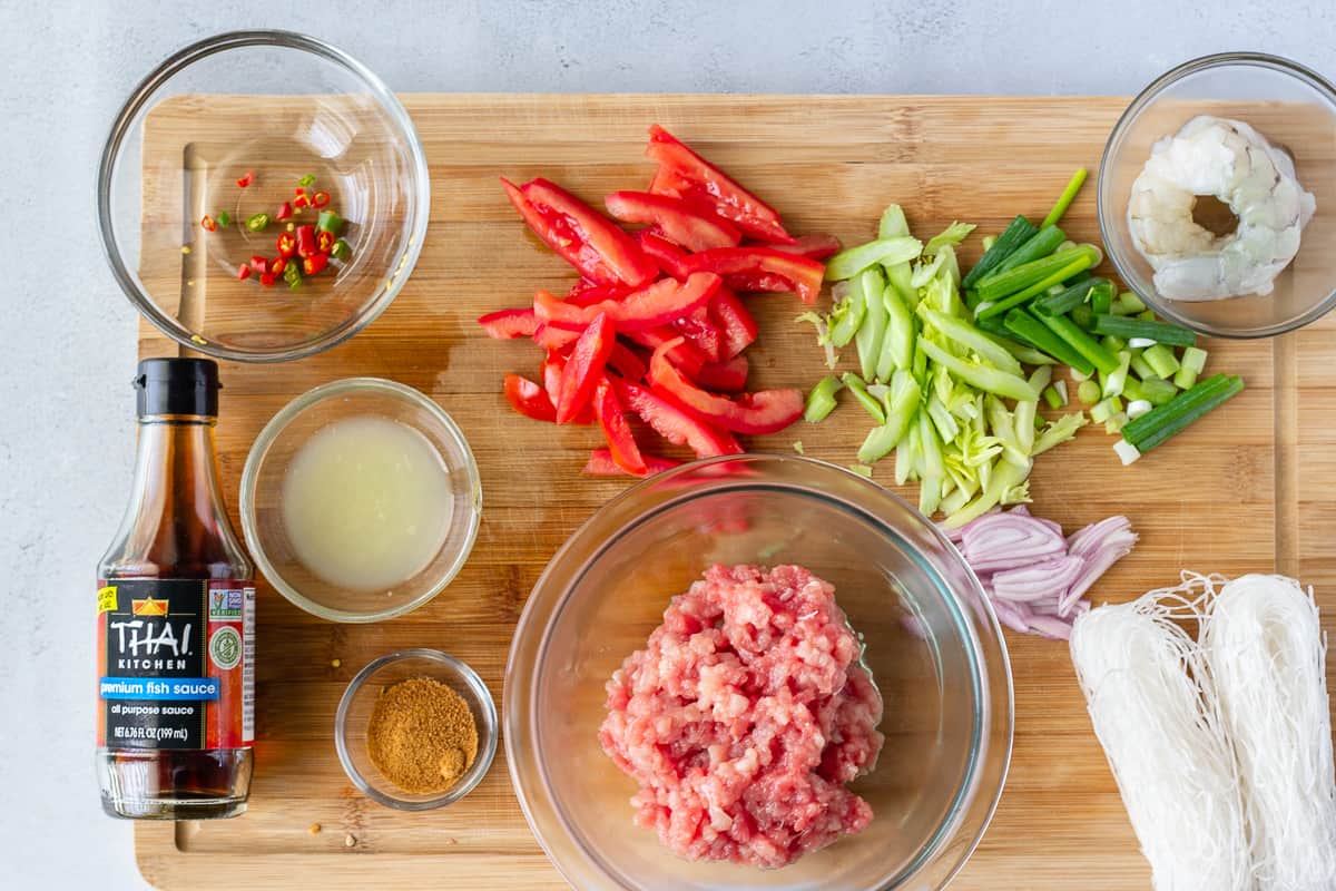 Ingredients for yum woon sen on a wood cutting board.