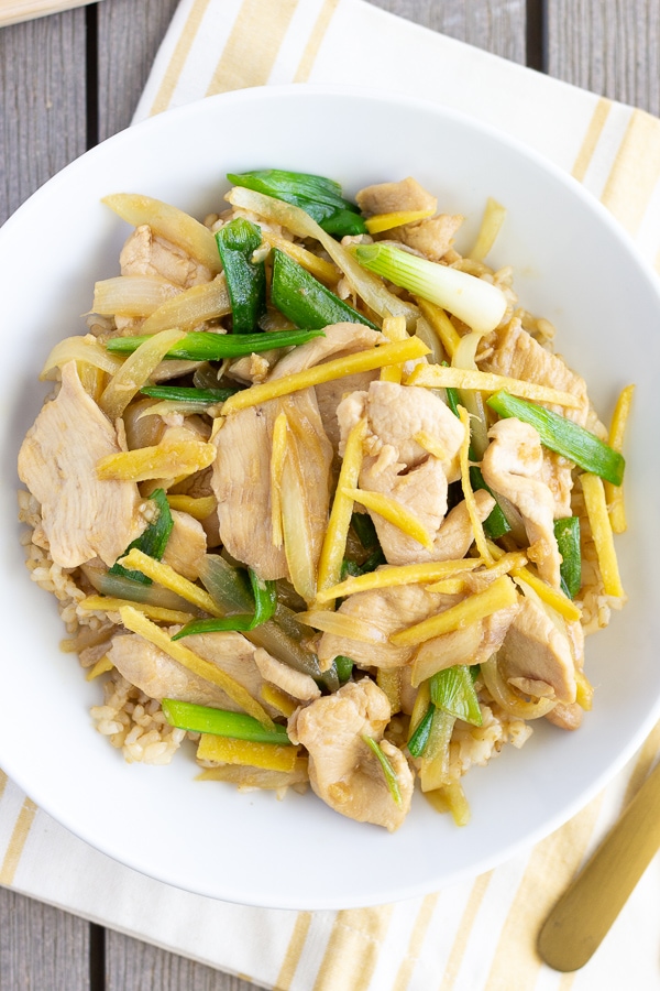 Gai pad khing in a white bowl with a yellow napkin underneath.