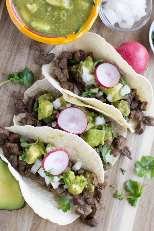 Overhead view of tacos on a cutting board. 