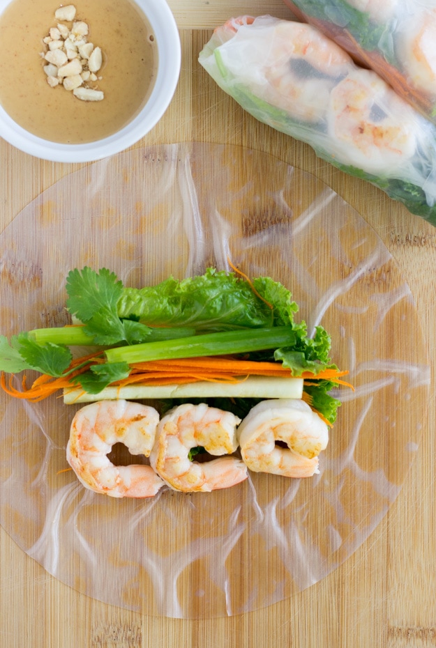 Rice paper on a cutting board and ingredients laid out on top.