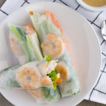 Overhead view of rice paper rolls on a plate with a side of peanut sauce.