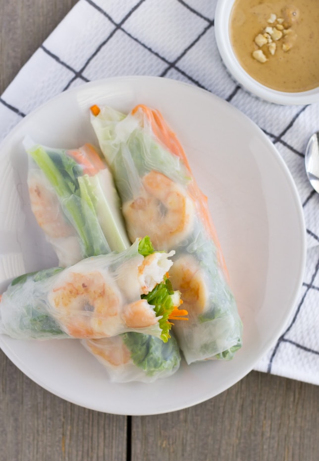 Overhead view of rice paper rolls on a plate with a side of peanut sauce.