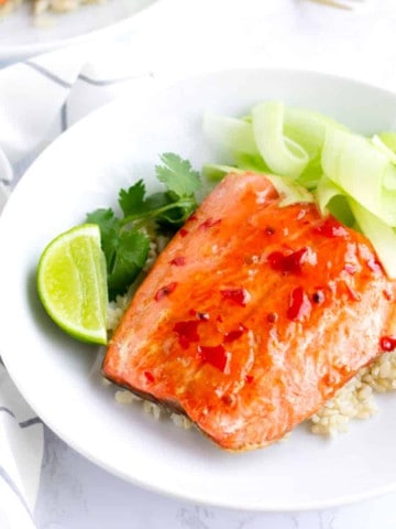 Chili Salmon on top of rice with ribbons of cucumber and a lime wedge.