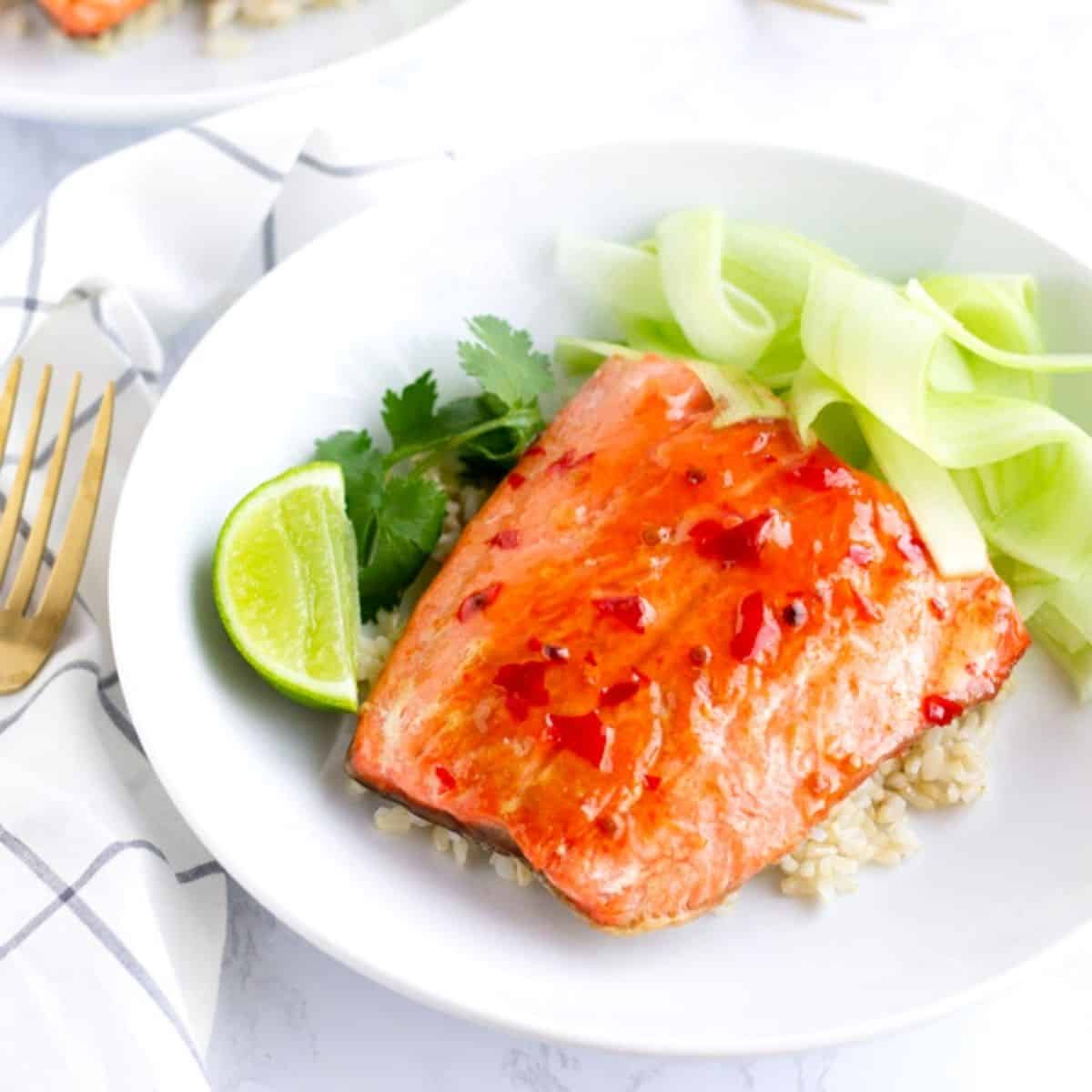 Chili Salmon on top of rice with ribbons of cucumber and a lime wedge.