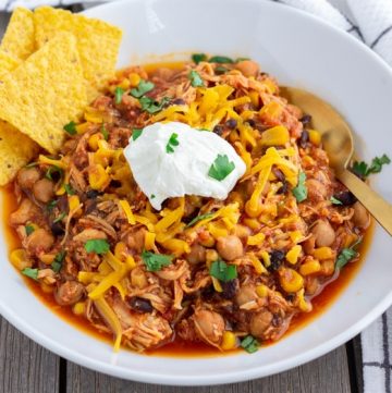 Landscape view of Chicken Taco Chili in a white bowl with a dollop of greek yogurt in the middle and tortilla chips on the side
