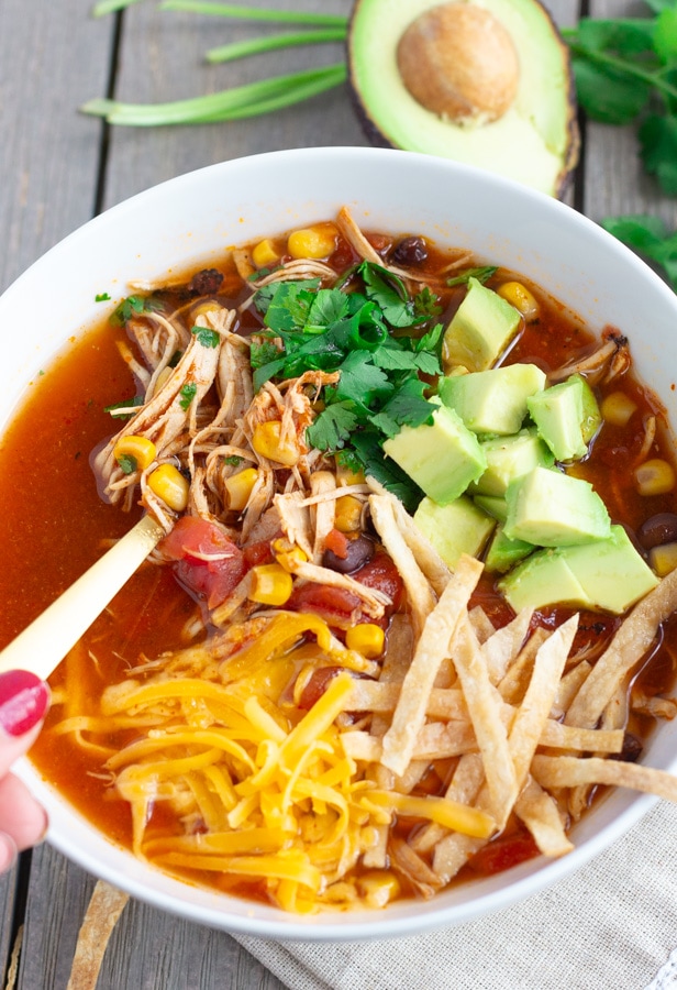 View of hand holding soup spoon in the chicken tortilla soup