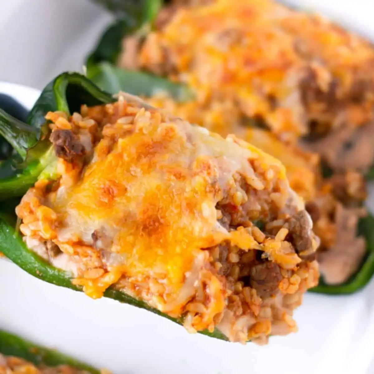 Stuffed Poblano being lifted from the pan of other poblanos.