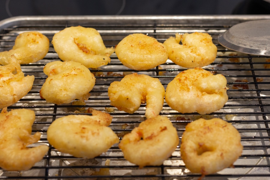 Fried shrimp pieces on a wire rack.