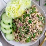 Overhead view of finished Larb Gai on a plate with lettuce and cucumbers.