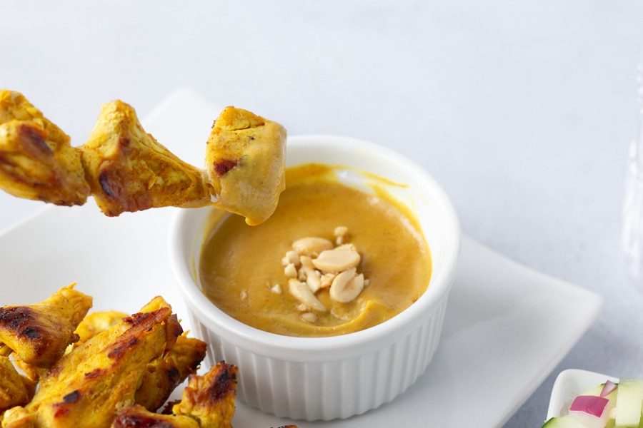 Chicken Satay being dipped into the peanut sauce.