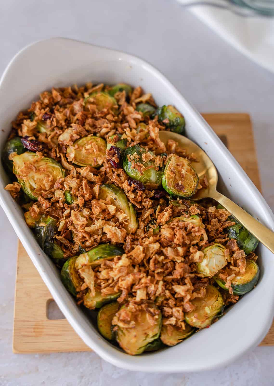 Maple and cranberry brussels sprouts in a dish with fried onions on top.