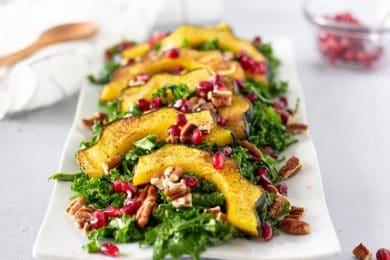 Complete kale salad with acorn squash and topped with pecans and pomegranates.