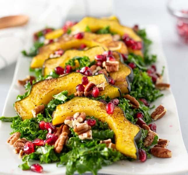 Complete kale salad with acorn squash and topped with pecans and pomegranates.