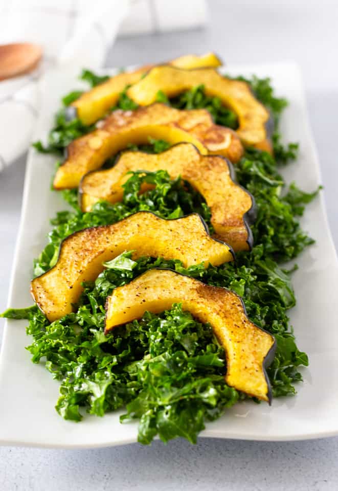 Kale Salad on a white plate topped with roasted acorn squash.