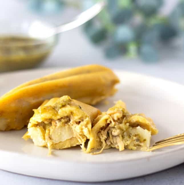 A Tamal on a plate that is cut in half to reveal the chicken filling