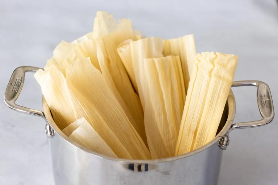 Stock pot filled with corn husks ready to be softened in hot water.