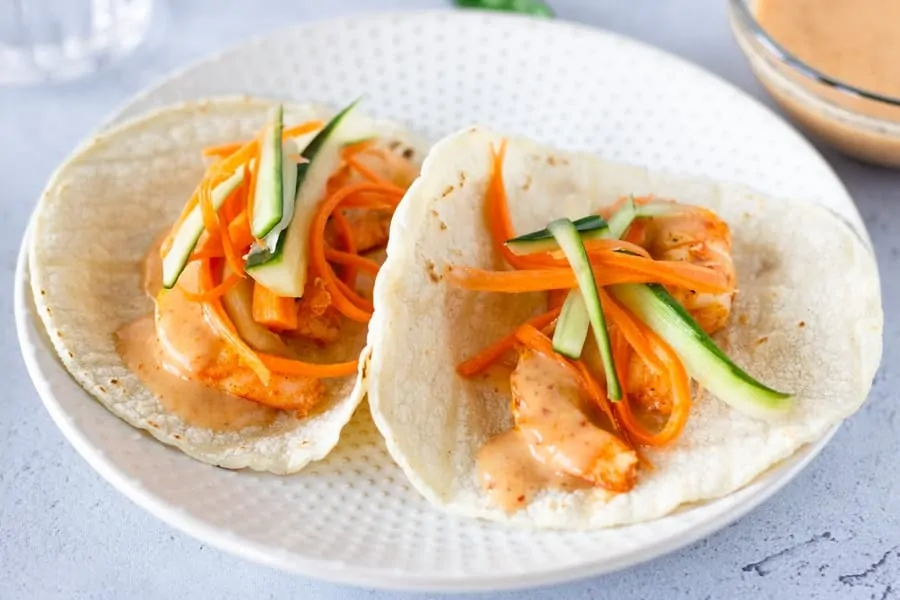 Two Tacos topped with pickled carrots and cucumbers.