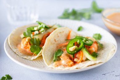 Completed Red Curry Tacos on a plate with red curry sauce on the side.