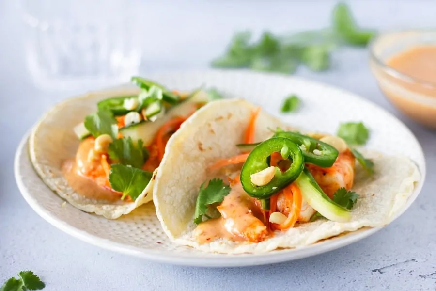 Completed Red Curry Tacos on a plate with red curry sauce on the side.