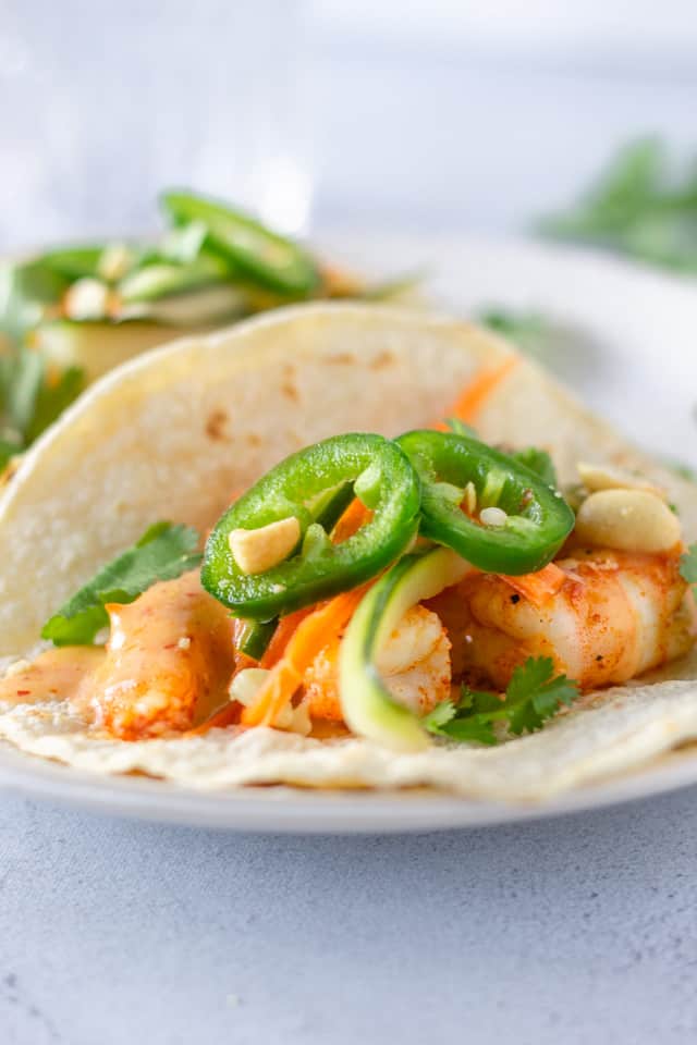 Up close view of shrimp tacos topped with sliced jalapenos.
