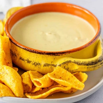 Feature image of queso in a yellow bowl with chips on the side.