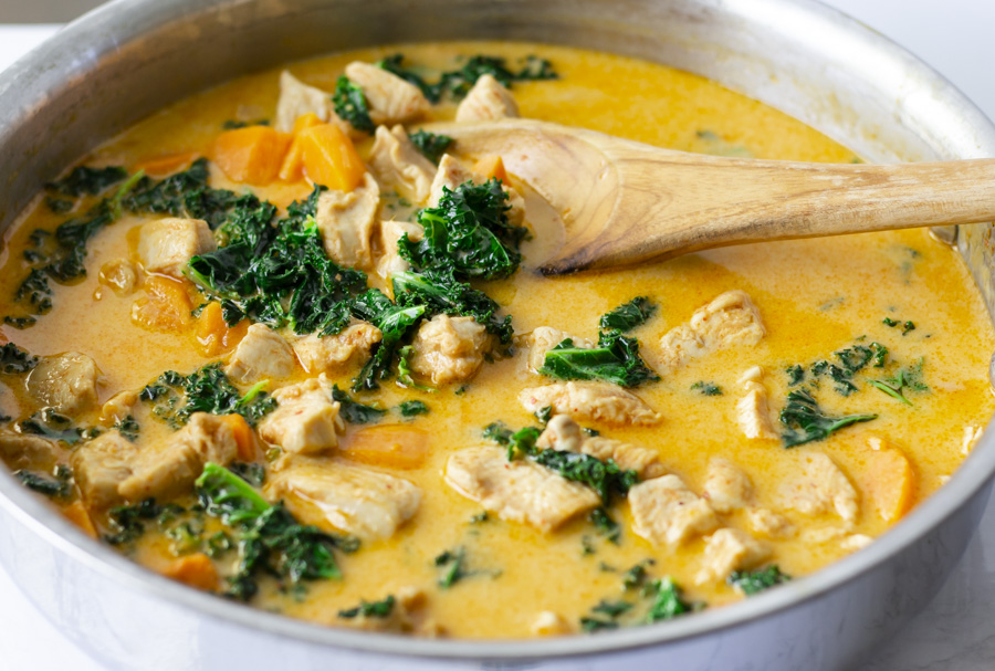 Curry in pot with a wooden spoon.