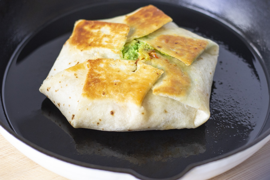 Crunchwrap being cooked in a cast iron skillet.