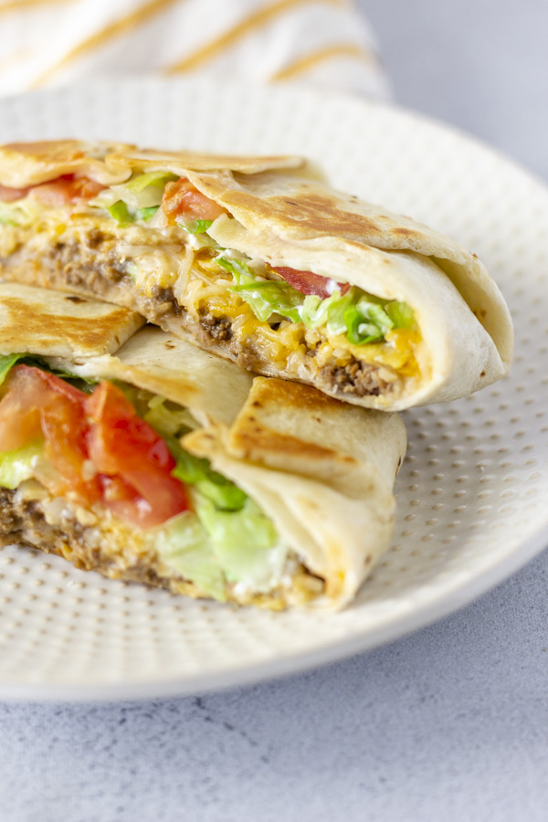 Crunchwrap cut in half and layered on top of each other on a plate.