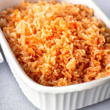 Red rice in a white serving dish.