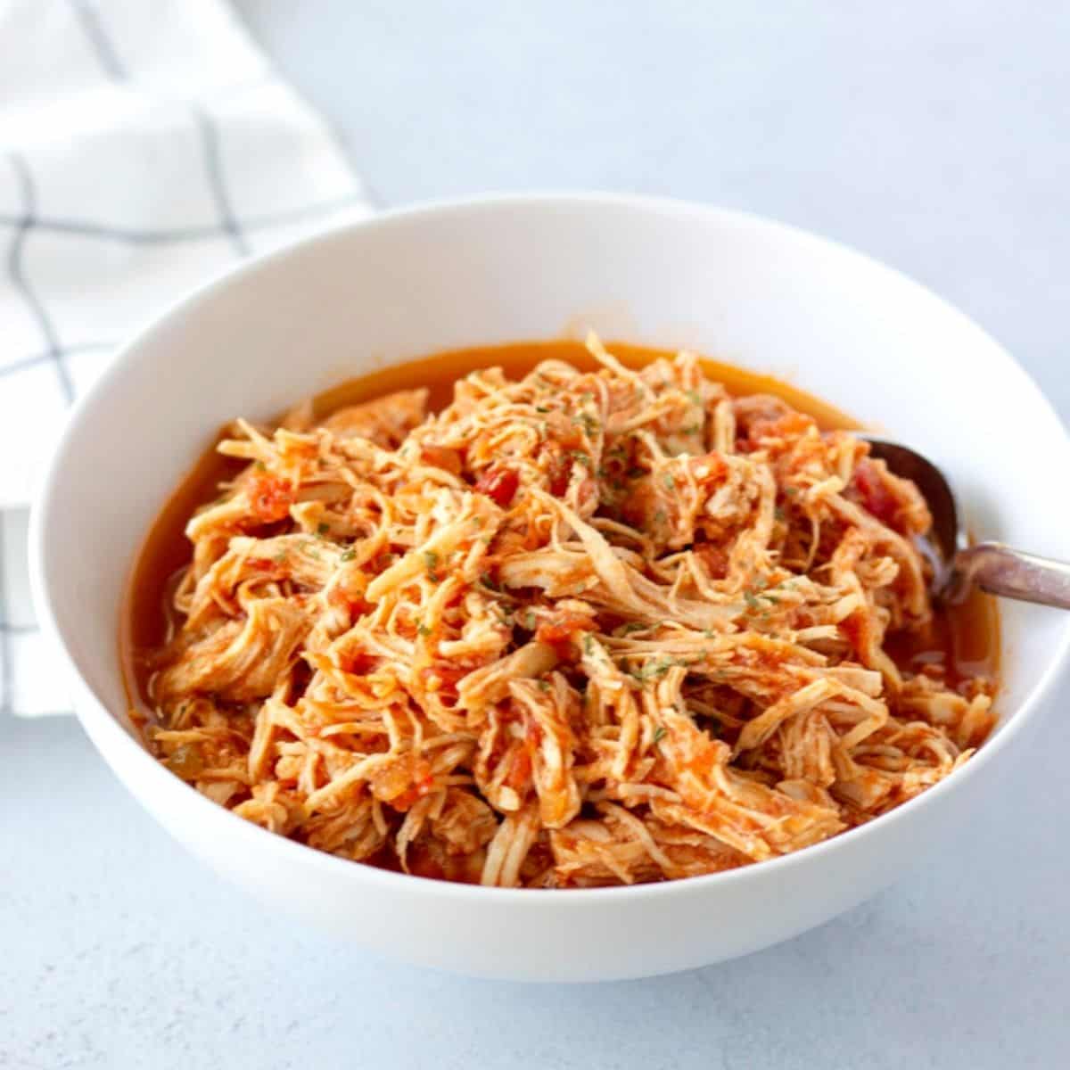 Shredded salsa chicken in a white bowl.