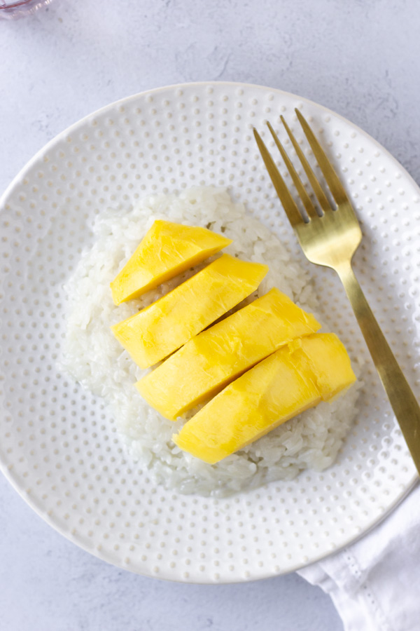 Overhead view of sticky rice with mango on a plate.