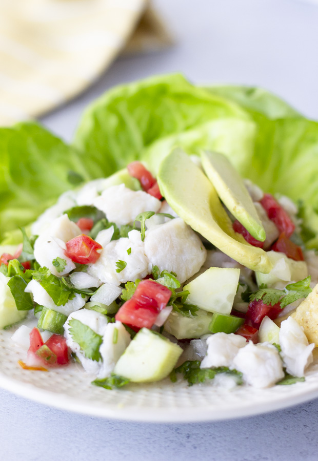 Fish ceviche on a plate with lettuce leaves and topped with avocado