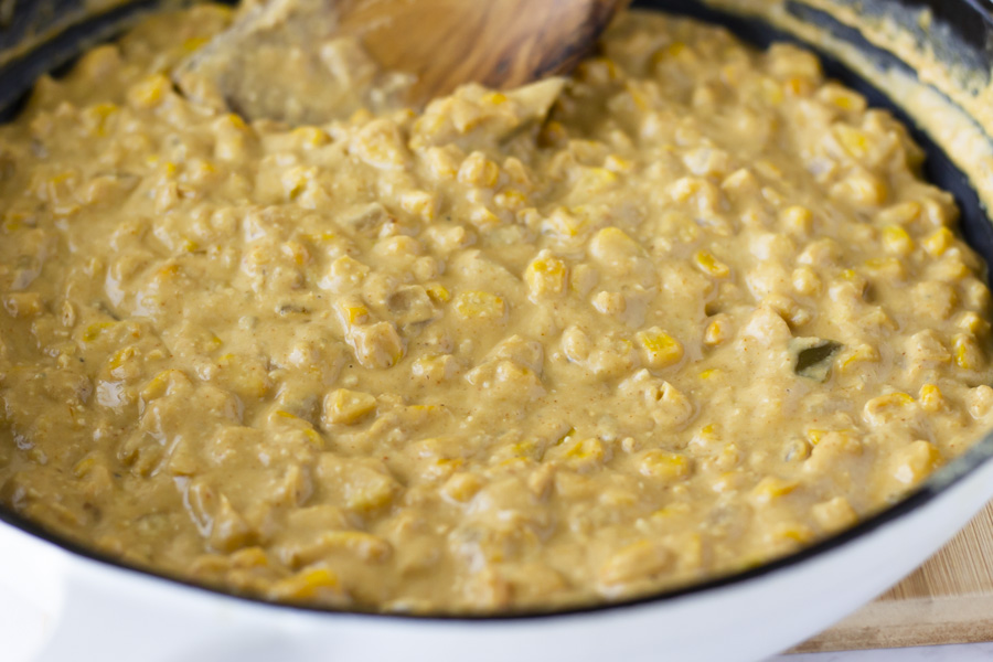 Cashew cream, corn, and onions cooking in a skillet.