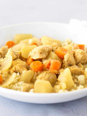 Up close view of yellow curry in a white bowl.