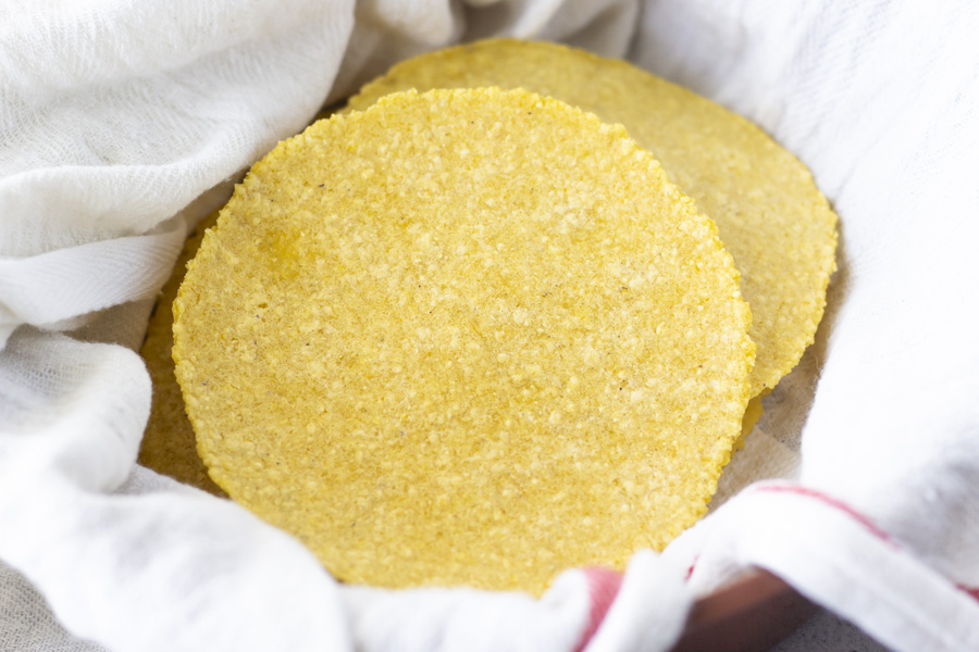 Up close view of yellow corn tortillas inside a kitchen towel.