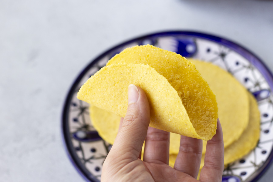 Hand hold a tortilla folding it in half.