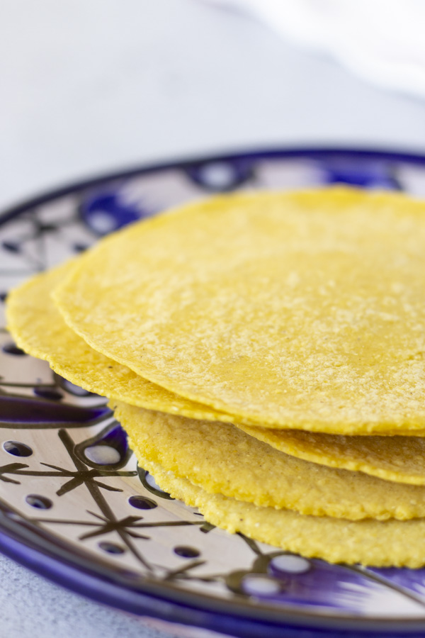 Blue plate with yellow tortillas stacked on top.