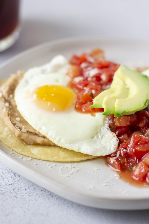 Up close view of sunny side egg on beans and corn tortilla.