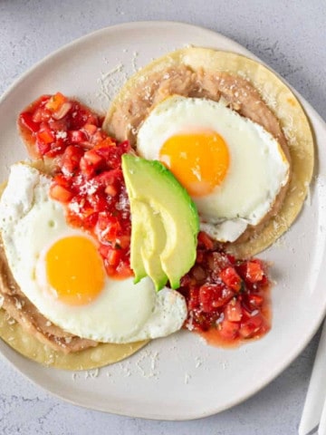 Overhead view of huevos rancheros on a white plate.