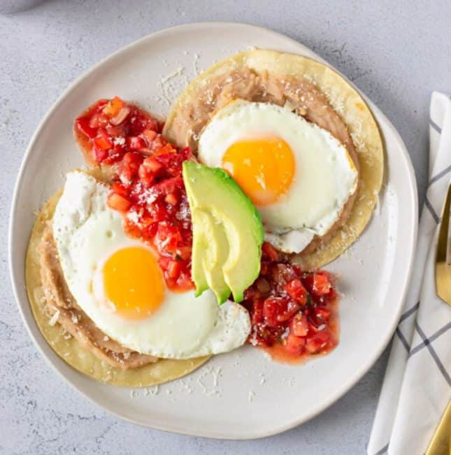 Overhead view of huevos rancheros on a white plate.