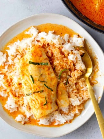Overhead view of red curry cod on a bed of white rice.