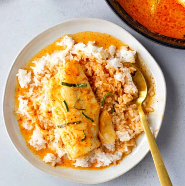 Overhead view of red curry cod on a bed of white rice.