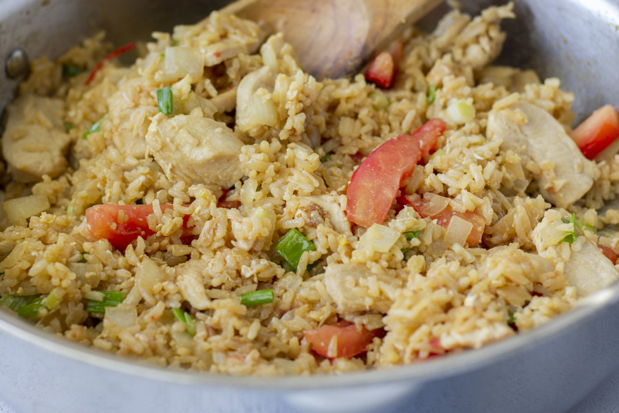 Fried Rice in a stainless steal skillet and a wooden spatula.