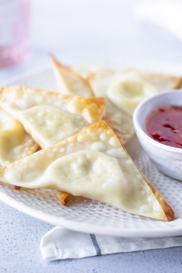 Up close view of cream cheese wonton on a plate with other wontons.